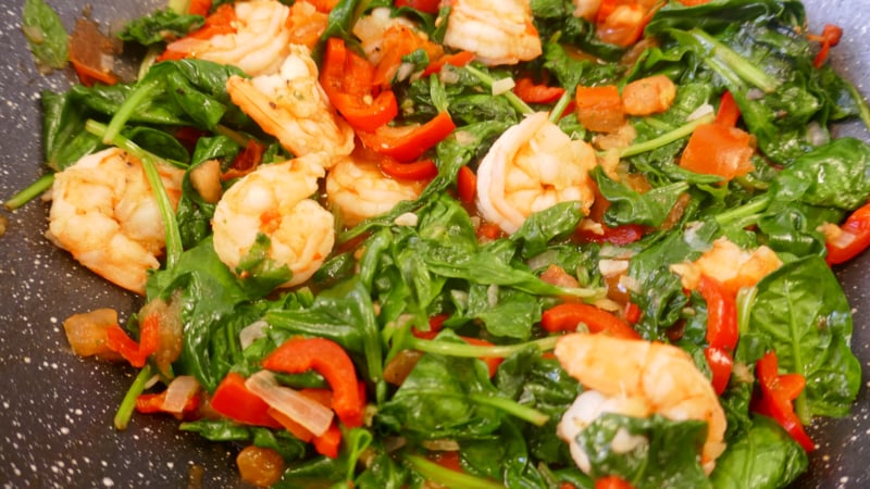 Aziatische wok met grote garnalen, spinazie en paprika
