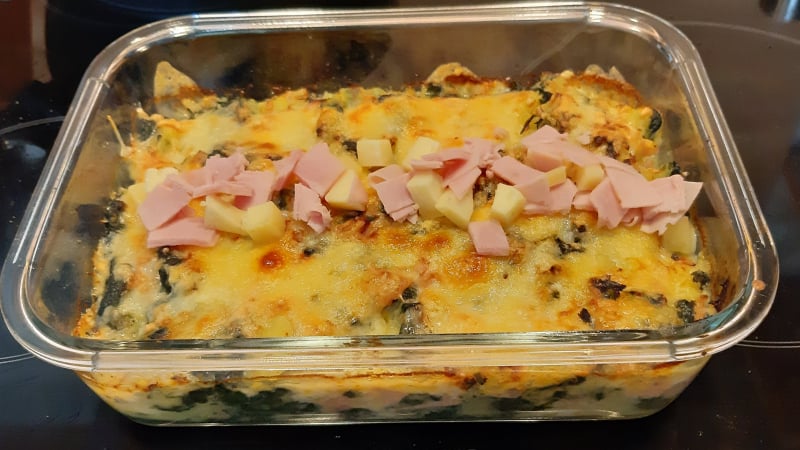Gegratineerde ovenschotel verse spinazie met aardappel, reepjes ham en blokjes kaas