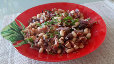 Witte bonensalade met knapperig gebakken Serranoham, gedroogde tomaten, olijven en dunne reepjes rode ui