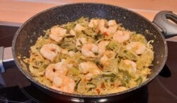 Pittig groentepannetje van spitskool, prei en paprika met grote garnalen